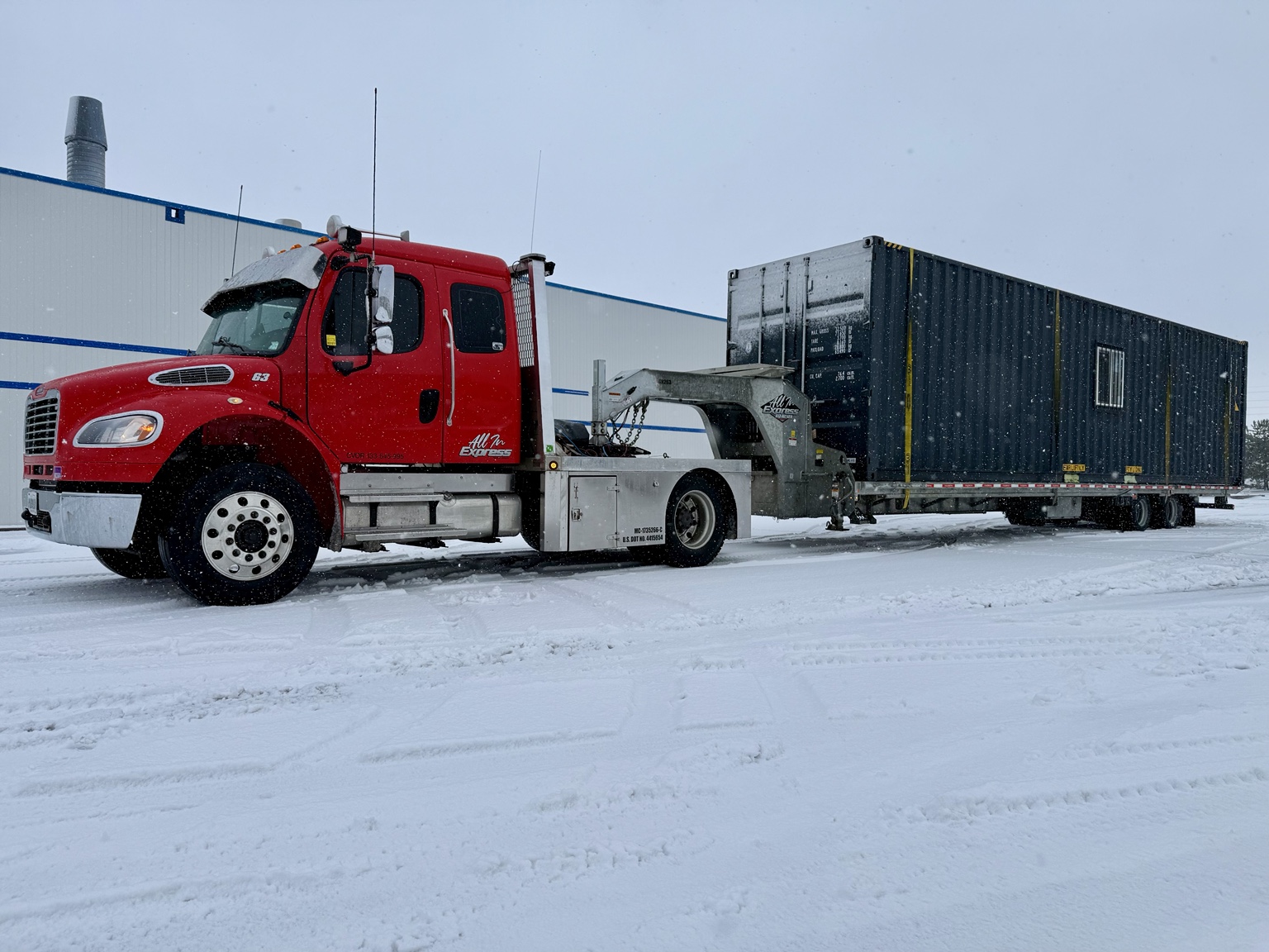 Red All In Express truck hauling container in winter